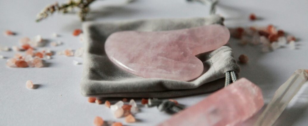 Grey backkground with a pink gua sha
