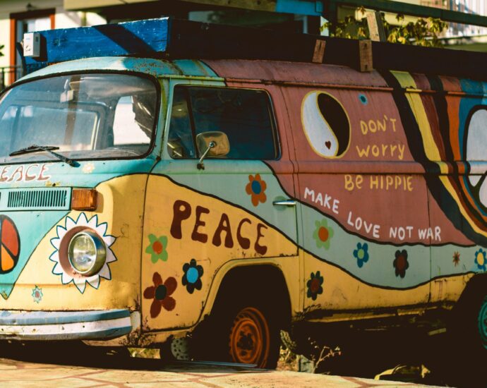 Blue and yellow Volkswagen hippie van with flowers and a peace symbol painted on
