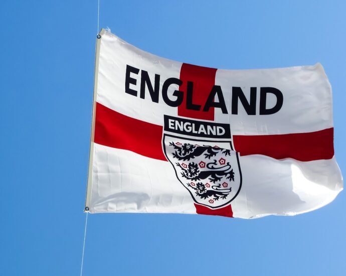 England flag (Red Cross over white) with English football team logo on it against blue sky