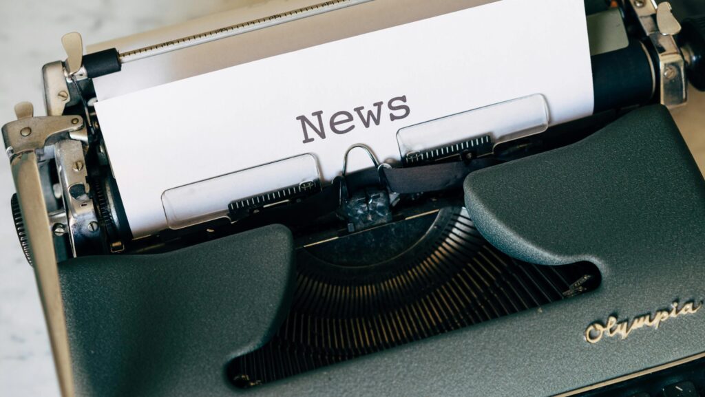 A piece of white paper in a type writer reading the word 'News'. My Journalism Journey
