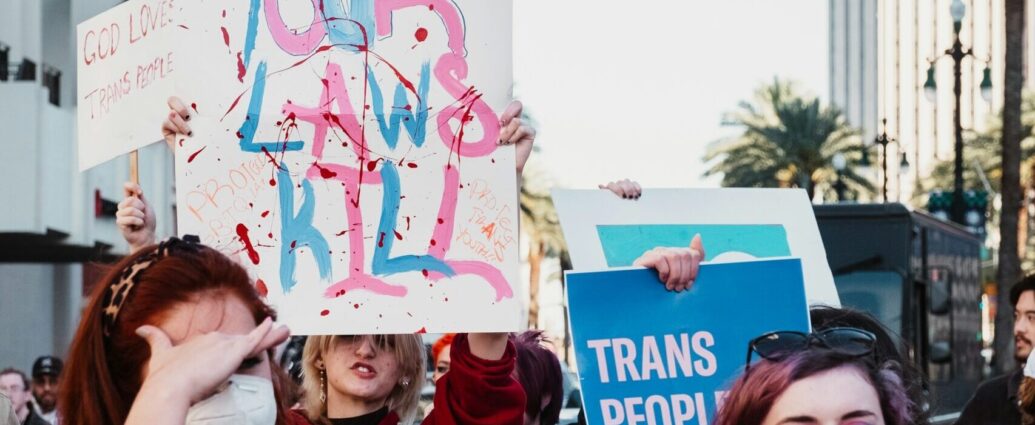 A group of people holding up signs about transgender women's rights and wearing masks.