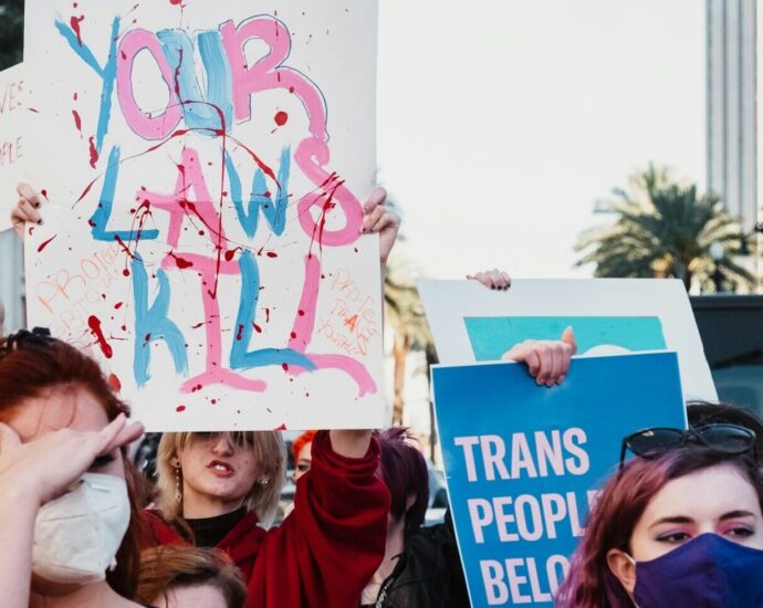 A group of people holding up signs about transgender women's rights and wearing masks.