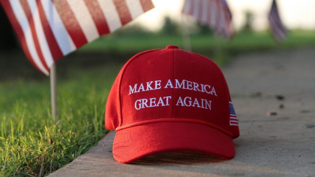 Red and white cap reading 'make America great again' on a concrete slab next to green grass