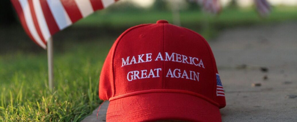 Red and white cap reading 'make America great again' on a concrete slab next to green grass