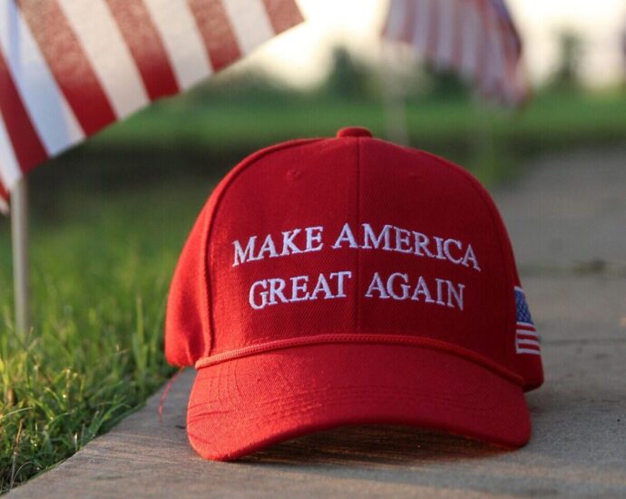 Red and white cap reading 'make America great again' on a concrete slab next to green grass