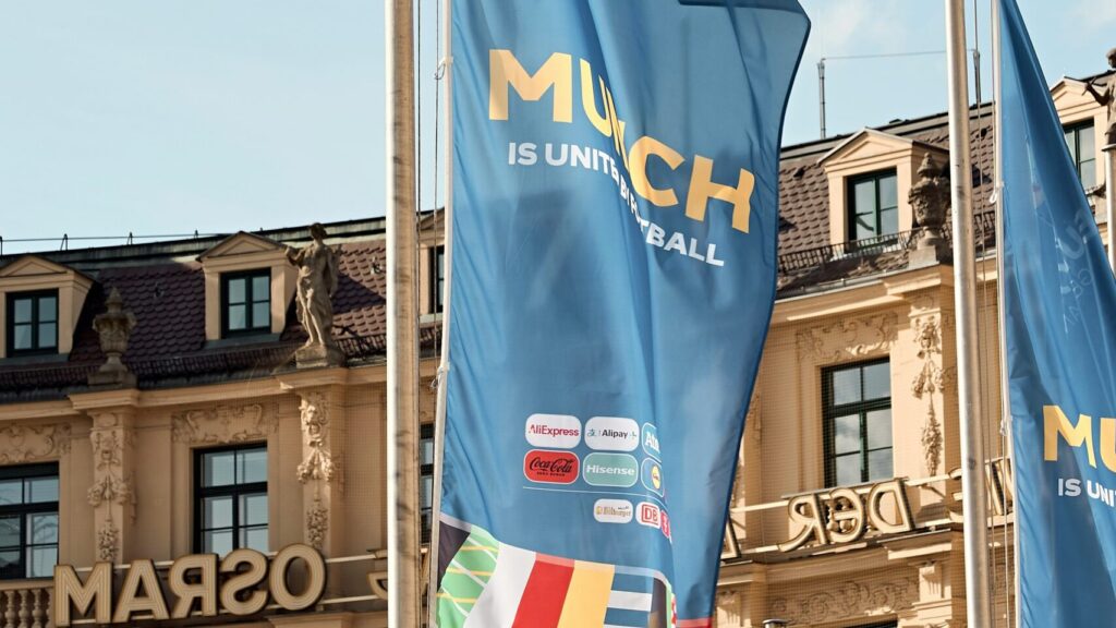 A bunch of flags in front of building. Group Stage.