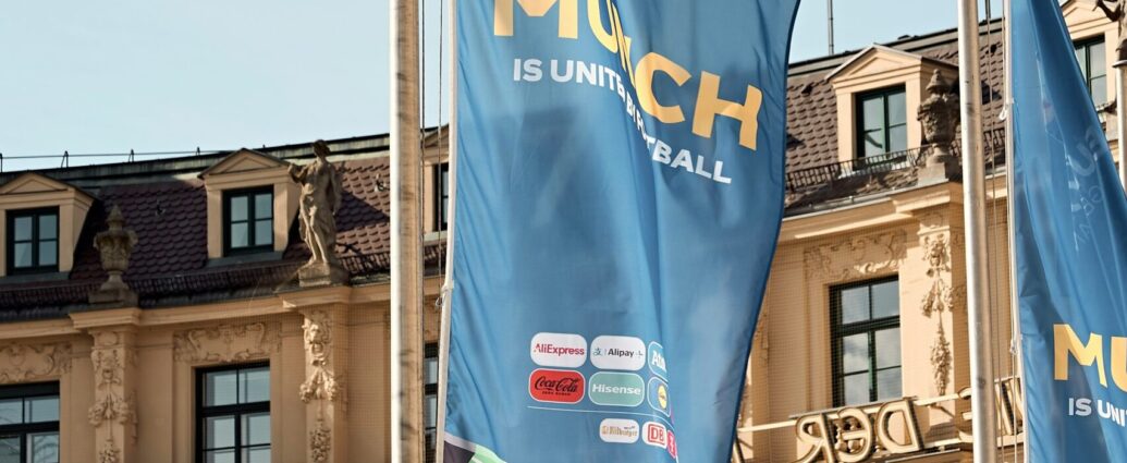 A bunch of flags in front of building. Group Stage.