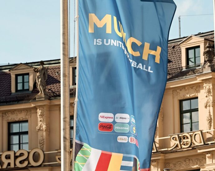 A bunch of flags in front of building. Group Stage.