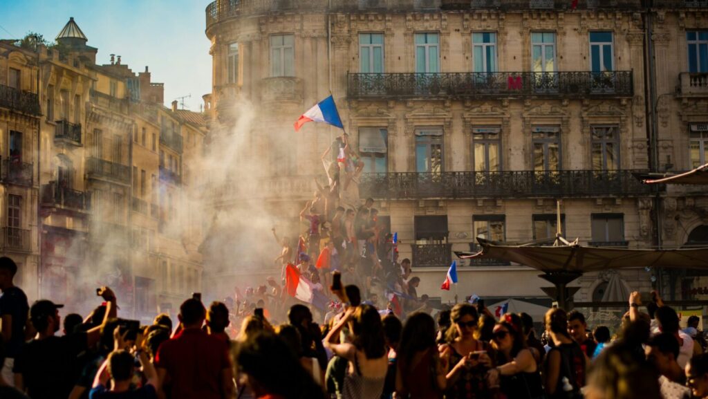 People climb a monument in France and fly a French flag from the top. France's recent election results showed a surprise victory for its left-wing coalition - but have we seen the last of their right-wing National Rally?