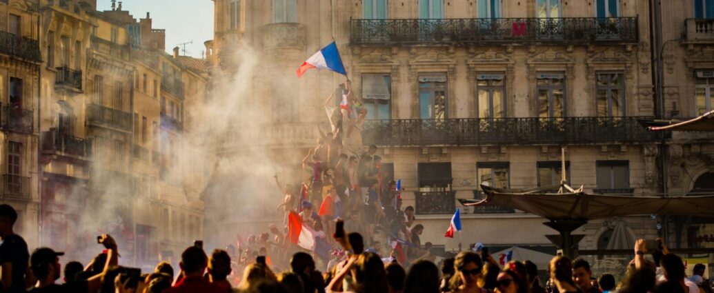 People climb a monument in France and fly a French flag from the top. France's recent election results showed a surprise victory for its left-wing coalition - but have we seen the last of their right-wing National Rally?