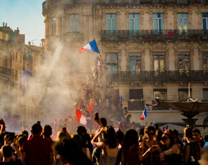 People climb a monument in France and fly a French flag from the top. France's recent election results showed a surprise victory for its left-wing coalition - but have we seen the last of their right-wing National Rally?