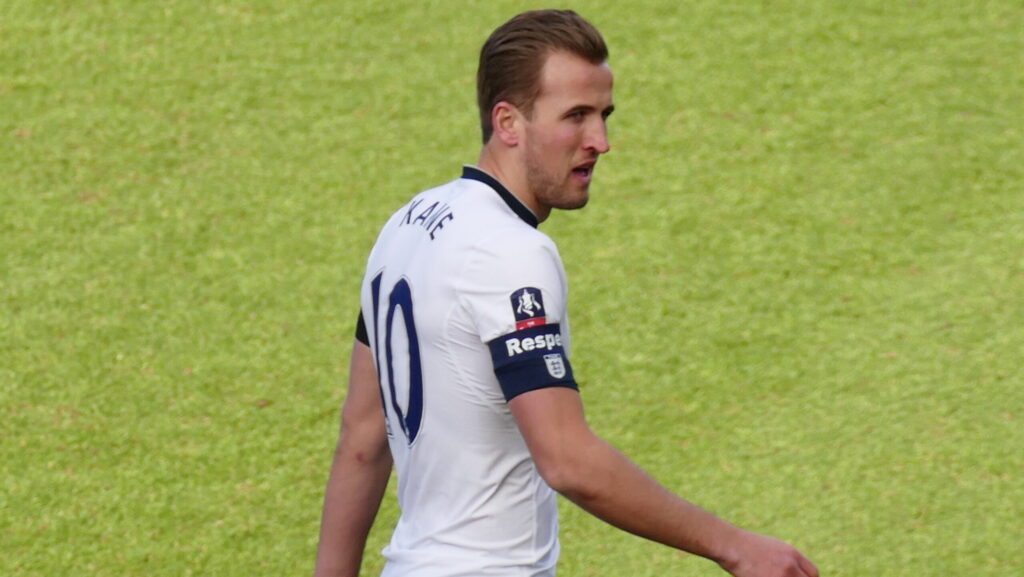 Harry Kane on football pitch in white Tottenham football kit