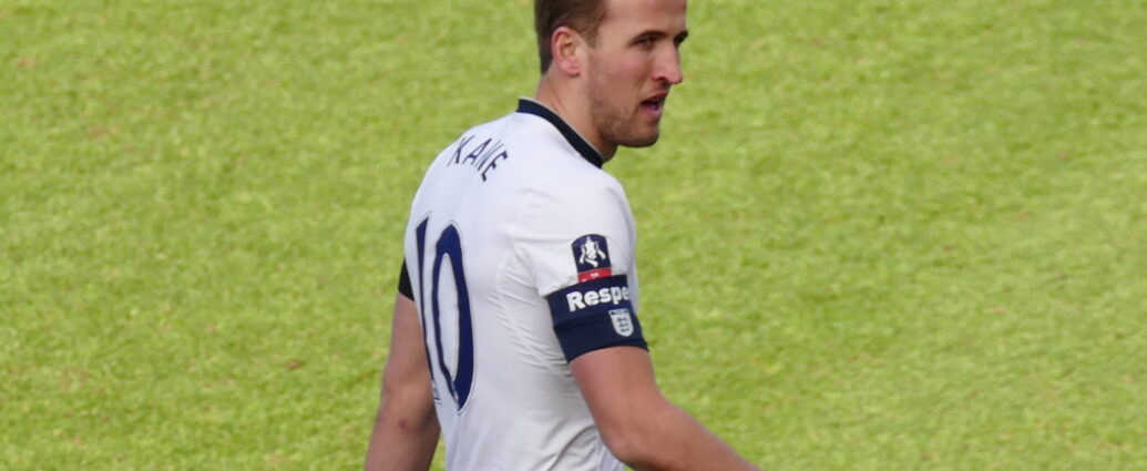 Harry Kane on football pitch in white Tottenham football kit