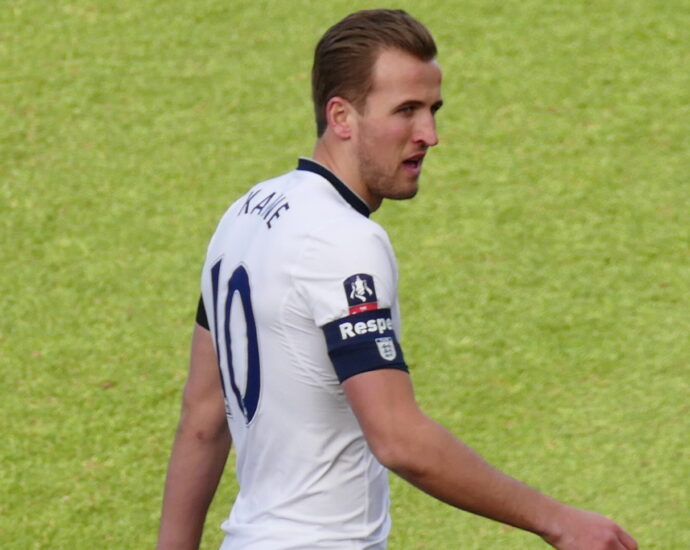 Harry Kane on football pitch in white Tottenham football kit