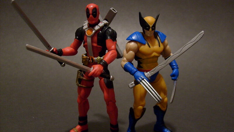 Deadpool & Wolverine figures. Action men figures one is red and navy, the other is yellow and blue, holding swords.