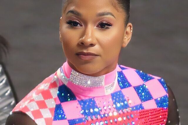 Jordan Chiles wearing pink and navy sequin gymnast costume with slicked back hair in a bun.