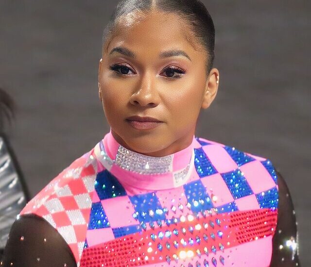 Jordan Chiles wearing pink and navy sequin gymnast costume with slicked back hair in a bun.