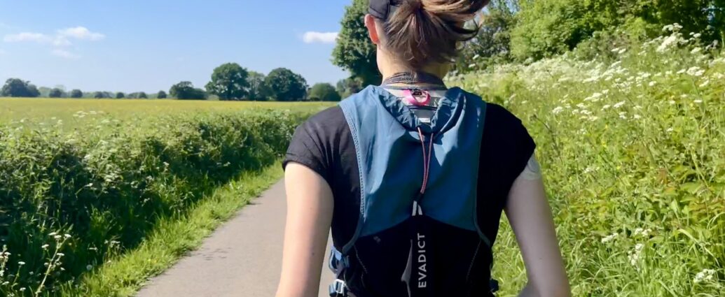 The back of a girl running with her hair in a ponytail, wearing a running vest as she tries Chi Running.