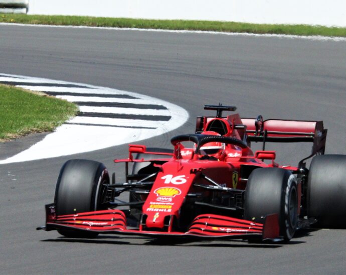 Charles Leclerc's red racing car with black wheels on racing track at Italian Grand Prix.