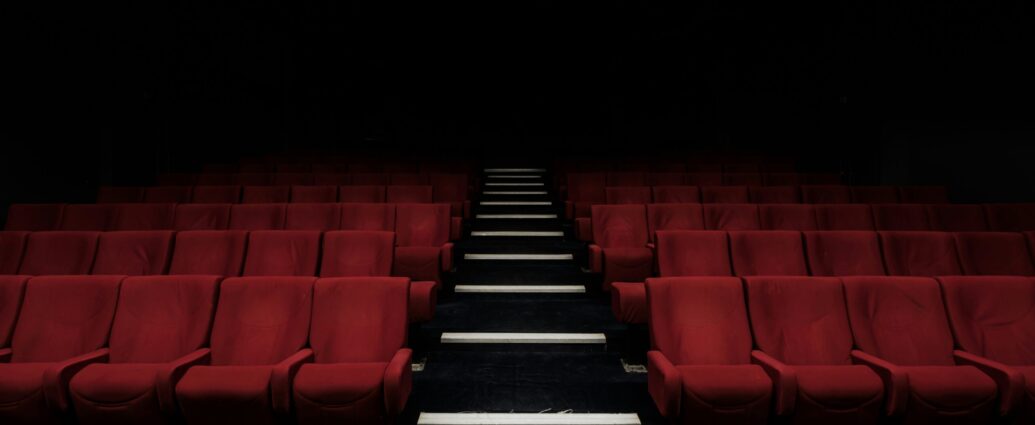 A dark cinema room with red chairs