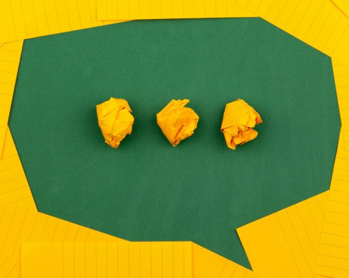 A speech bubble cut out of green paper, with three dots made from scrunched up yellow paper, indicating someone is about to talk in the MLE dialect.