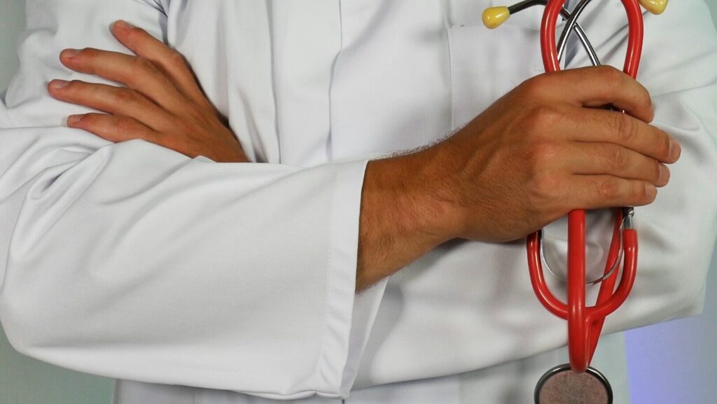 a health professionals wearing white medical jacket holding stethoscope