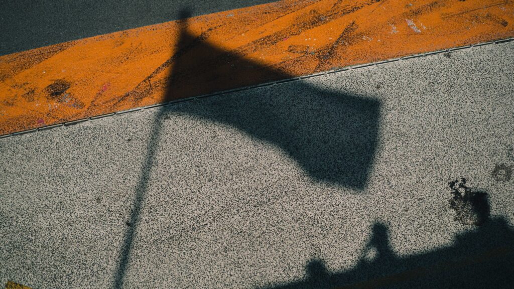 Franco Colapinto. A shadow of a Formula One flag on concrete floor.