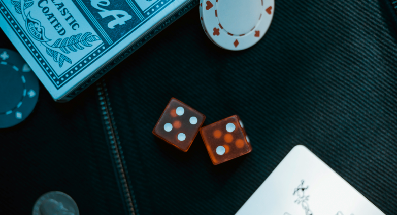 Two orange dice on black surface with poker coin representing Joker: Folie á Deux