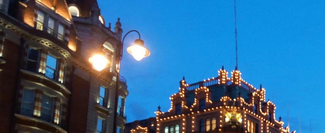 A city street at night with Harrods building lit up