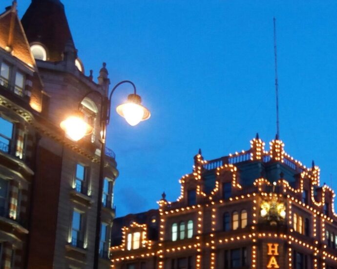 A city street at night with Harrods building lit up