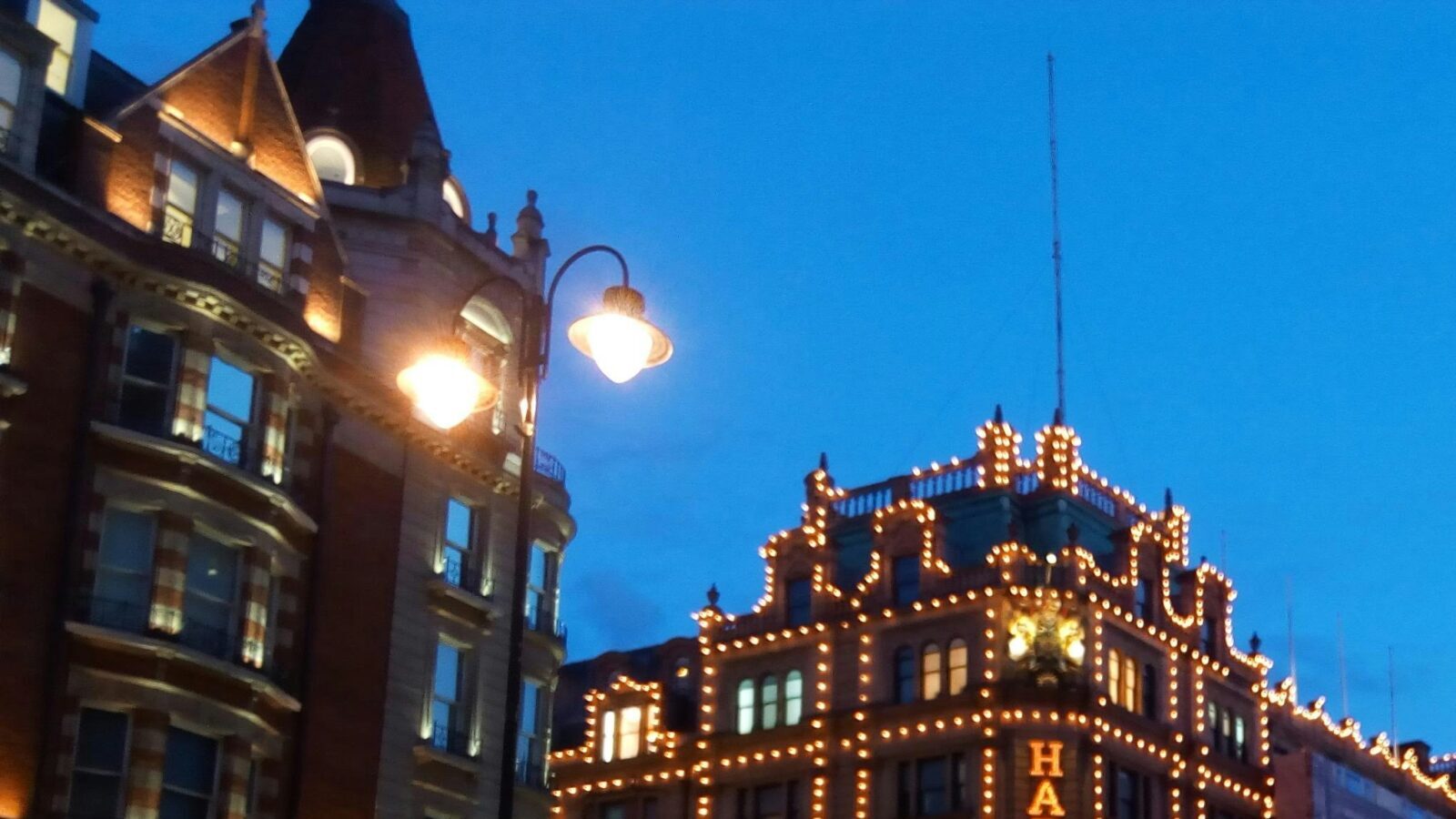 A city street at night with Harrods building lit up