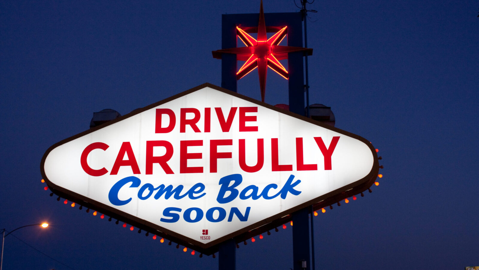 Las Vegas neon sign reading 'drive carefully' in red capital letters and 'come back soon' in blue