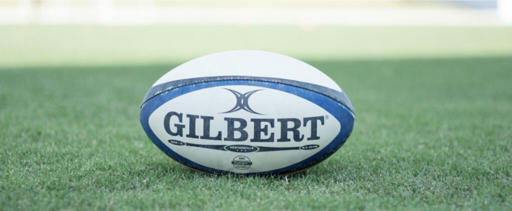 A white and blue rugby pall on green grass