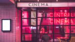 Cinema with neon sign and people sitting inside