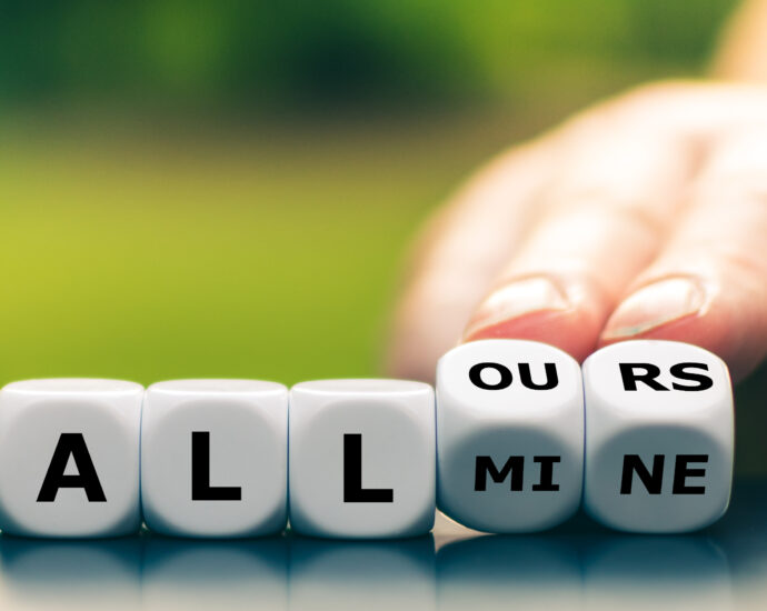 A hand turns the last two dice in a row of five, changing the expression "all mine" to "all ours".