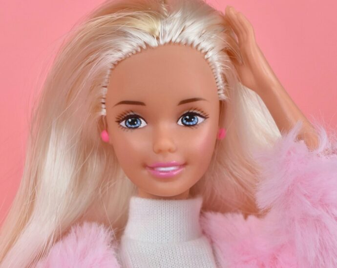 A blonde Barbie Doll wearing a pink jacket