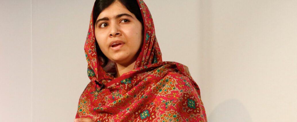 Photo of Malala Yousafzai sitting in a chair, looking off to the side, wearing a red and green patterned dupatta