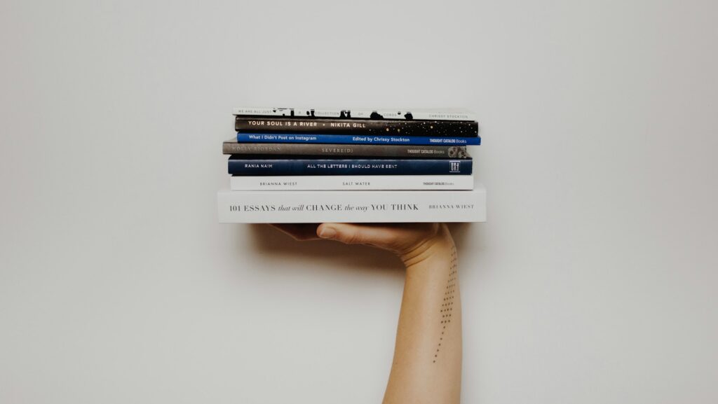 A pile of books held up in the air, balanced on an outstretched hand. Featured photo of an article