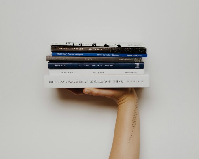 A pile of books held up in the air, balanced on an outstretched hand. Featured photo of an article