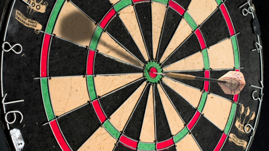 Close up photo of a darts board with a dart in it.