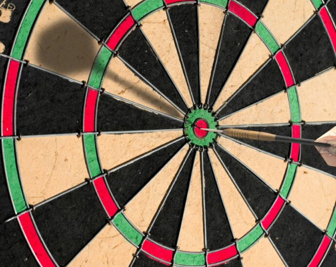 Close up photo of a darts board with a dart in it.