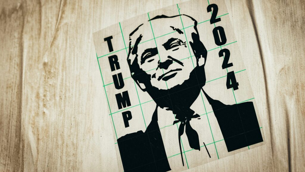 A black ink drawing of Donald Trump with the words 'Trump 2024' on a wooden surface.