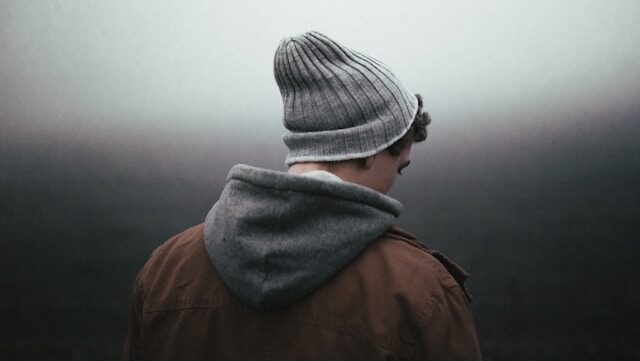 A man wearing a beanie with his back to the camera